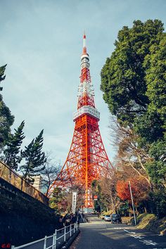 a very tall red and white tower sitting next to trees on the side of a road