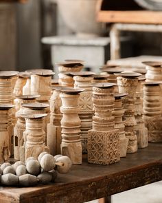 many vases are sitting on a table with balls in the foreground and one is made out of wood