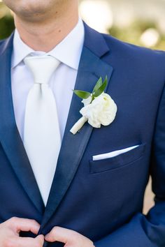 a man in a blue suit with a white flower on his lapel