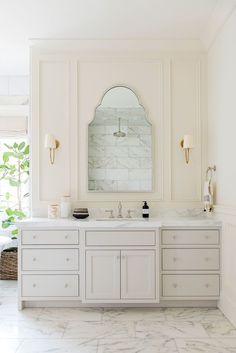 a white bathroom with two sinks and a large mirror on the wall over it's vanity