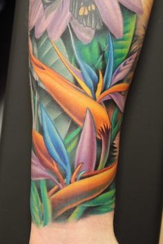 a colorful tattoo on the arm of a person with flowers and leaves in it's center