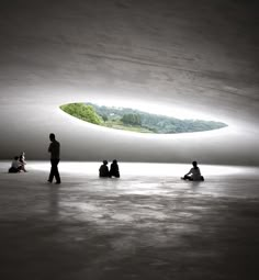 people are sitting and standing in the middle of a room with a skylight above them