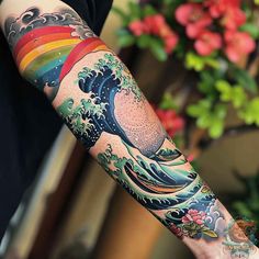 a person with a tattoo on their arm holding a colorful wave and rainbow in the sky