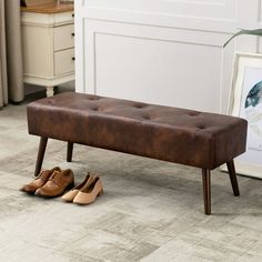 a brown bench sitting on top of a wooden floor next to a pair of shoes