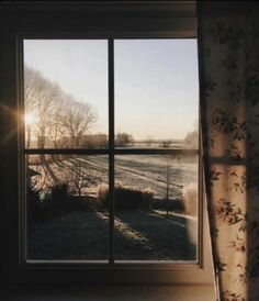 an open window with the sun shining in it's shadow and frosty field outside