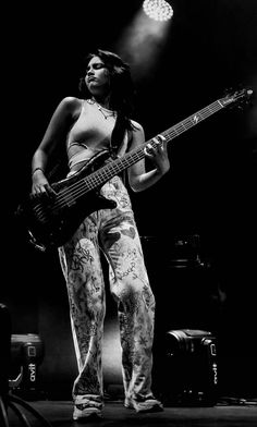 a woman holding a bass guitar on stage