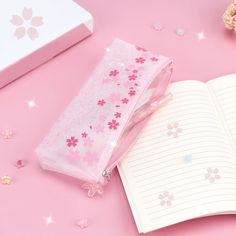 an open notebook sitting on top of a table next to a pink flowered bag