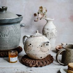 an old teapot sits on a table next to cookies and other items that are sitting around it