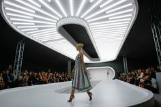 a woman walking down a runway in front of a crowd