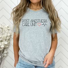 "This one of a kind t-shirt proudly portrays the Post-Anesthesia Care Unit name and is a perfect gift to give for Med Student Grads, Nurses Week, PACU Team and Staff, Moms, Sisters, Brothers, Dads, or Doctors in your life!  Our super soft tee can be worn in the Spring, Summer or Fall to show off your appreciation for those hard working Healthcare professionals helping all of feel better after surgery! Popular Right Now!! This classic unisex jersey short sleeve tee fits like a well-loved favorite. Soft cotton and quality print make users fall in love with it over and over again. These t-shirts have-ribbed knit collars to bolster shaping. The shoulders have taping for better fit over time. Dual side seams hold the garment's shape for longer.  .: 100% Airlume combed and ringspun cotton (fiber Nursing Graphic Tee With Short Sleeves, Pre-shrunk Nursing T-shirt With Crew Neck, Nursing Cotton T-shirt With Crew Neck, Cotton Nursing T-shirt With Crew Neck, Crew Neck Cotton T-shirt For Nursing, Cotton Crew Neck Nursing T-shirt, Nursing Tops With Text Print And Crew Neck, Crew Neck Nursing Tops With Text Print, Med Student