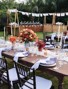 an outdoor table set with place settings and flowers in vases on the tables for dinner