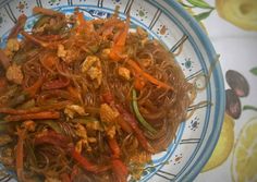 a bowl filled with noodles and vegetables on top of a tablecloth covered table cloth