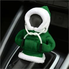 a green and white stuffed animal sitting in the center console of a car with its hood up