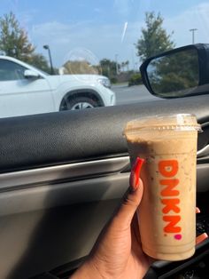 a woman holding up a drink in her car