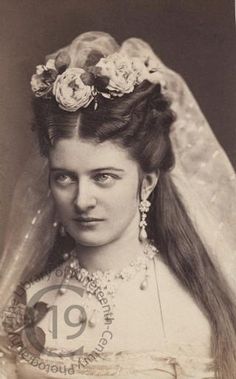 an old black and white photo of a woman wearing a veil with flowers in her hair