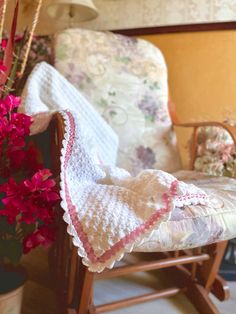 a crocheted blanket sitting on top of a chair next to a flower pot