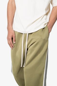 the Relaxed Tricot Track Pants are designed with a custom-developed, 300 GSM single-layer tricot fabric, featuring a contrasting striped panel down the side leg and an extended drawcord details relaxed fit 65% polyester 35% cotton custom developed heavyweight tricot fabric model is 6’1, 160 lbs and wears a size medium Casual Green Bottoms With Three Stripes, Green Side Stripe Pants For Streetwear, Green Streetwear Pants With Side Stripes, Green Pants With Side Stripes For Streetwear, Green Sweatpants With Side Stripes For Streetwear, Cotton Joggers With Three Stripes In Relaxed Fit, Sporty Cotton Pants With Three Stripes, Green Bottoms With Side Stripes For Streetwear, Green Athleisure Bottoms With Side Stripes