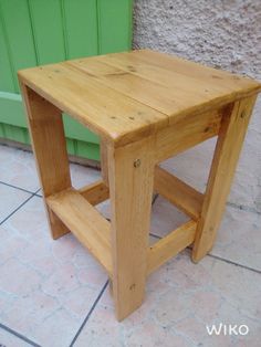 a small wooden table sitting on top of a tile floor next to a green door