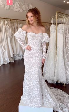 a woman standing in front of some wedding dresses