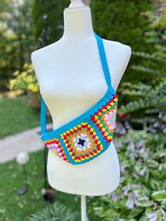 This handmade bum bag is perfect for those who love a boho and festival style. It is crafted with colorful granny squares, each crocheted with care and attention to detail. The vibrant squares stand out against a beautiful turquoise background, adding a pop of color to any outfit. The crochet free bag is designed to be worn as a sling bag, providing both style and functionality. It offers a spacious compartment to keep your essentials organized and easily accessible.  Whether you're heading to a music festival, exploring a new city, or simply running errands, this fanny pack is a convenient and trendy accessory. Made with love and attention to detail, this crochet chest bag is a one-of-a-kind piece that adds a touch of creativity and uniqueness to your style. It's not just a bag; it's a st Handmade Turquoise Bags For Summer, Handmade Turquoise Summer Bag, Handmade Blue Crochet Bag For Festival, Blue Bohemian Crochet Bag For Festival, Multicolor Belt Bag For Everyday Summer Use, Bohemian Turquoise Bags For Festival, Bohemian Blue Shoulder Bag For Festivals, Bohemian Belt Bag For Everyday Use, Turquoise Bags For Festivals