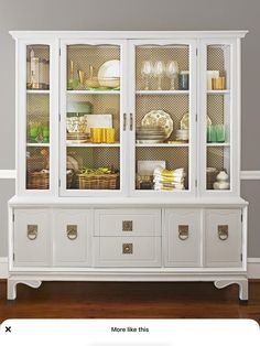 a white china cabinet with glass doors and drawers on the bottom, sitting in a living room