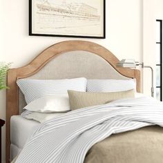 a bed with blue and white striped comforter in front of a painting on the wall