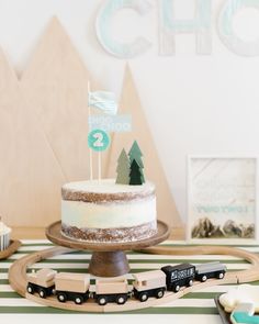 a train themed birthday party with a cake and cupcakes on a table top