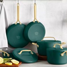 green pots and pans hanging from hooks in a kitchen with lemon slices on the counter