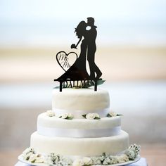 a wedding cake with a silhouette of a bride and groom holding a heart on top