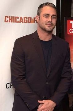 a man in a suit standing next to a poster for the chicago fire department's tv series