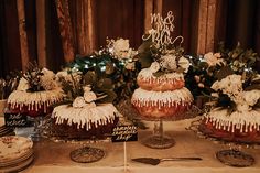 three cakes with icing and flowers are on a table next to plates, forks and utensils