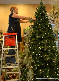 a woman is decorating a christmas tree