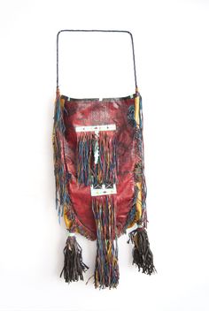 a red purse with tassels hanging from it's side on a white background