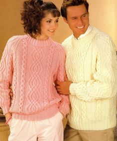 two people in sweaters and pants standing next to each other with their arms around one another