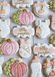 many decorated cookies are arranged on a white wooden table with pumpkins and other decorations