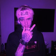 a man with pink hair and tattoos making the peace sign