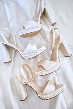 three pairs of white high heeled shoes with pearls on the toes and heels, all in satin material