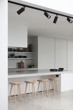 three stools in front of a kitchen island with lights hanging from it's ceiling