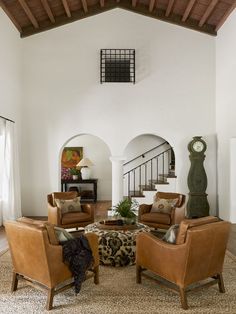 a living room filled with lots of furniture and a clock mounted on the wall above it