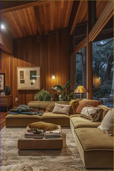 a living room filled with lots of furniture next to a large window covered in wood paneling