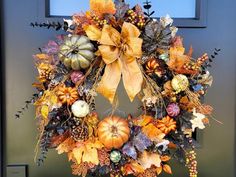 a wreath that has been decorated with autumn leaves and pumpkins