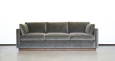 a gray couch sitting on top of a hard wood floor next to a white wall