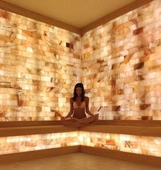 a woman is sitting in the middle of a room with stone walls and flooring