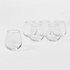 six wine glasses sitting next to each other on a white surface with one empty glass in the middle