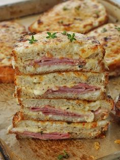 four sandwiches stacked on top of each other with cheese and meat in the middle one is cut in half