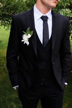 a man in a black suit and white flower boutonniere