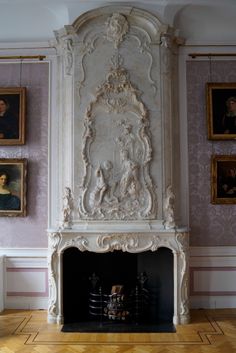 an ornate fireplace with paintings on the wall