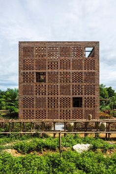 a building made out of wooden blocks in the middle of a field with green plants