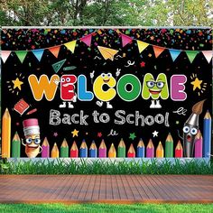 a welcome back to school sign in front of a wooden deck with grass and trees