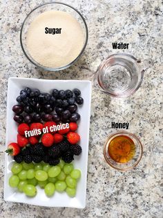 grapes, strawberries, and other fruits are arranged on a plate next to a measuring cup